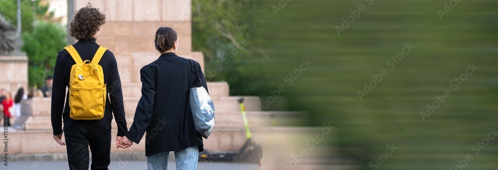 Wall mural Young couple walking holding hands