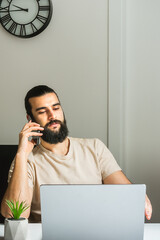 A young businessman works from home on a laptop computer and makes business calls. A businessman...