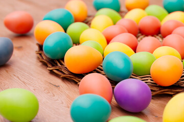 Obraz na płótnie Canvas Multicolored Easter Eggs Arranged in Basket on Rustic Wooden Table