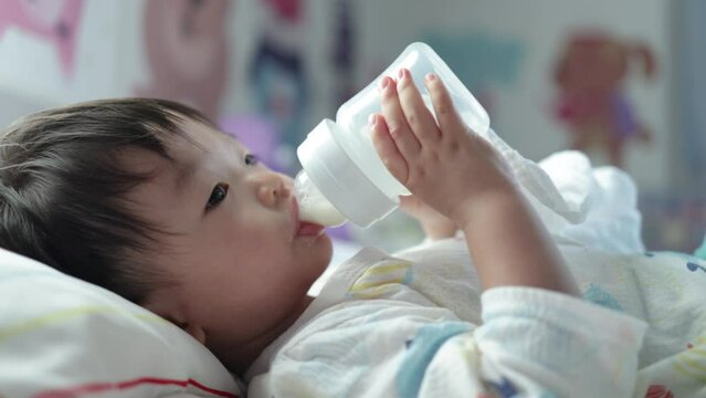 Asian Chinese baby boy drinking milk with holding milk bottle by him self.