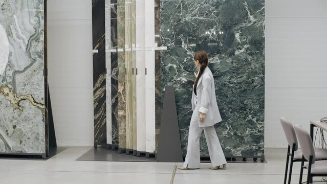 Woman walking in front of marble wall in tile showroom