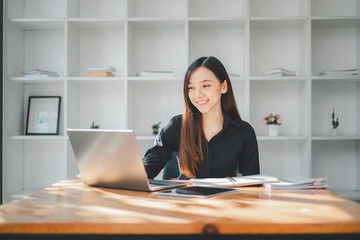A smiling professional woman is fully engaged with her laptop in a minimalist and bright office space, reflecting the modern simplicity of today's work environment.