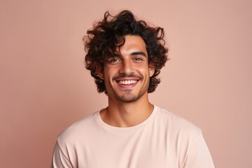 Fototapeta na wymiar Portrait of a cheerful young man with curly hair on a pink background