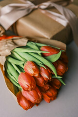 Bouquet of red tulips and a gift box with a bow, festive concept