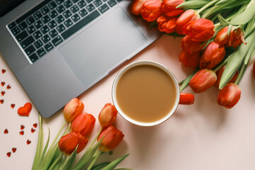 Cup of coffee, bouquet of red tulips and laptop top view flat lay, festive background