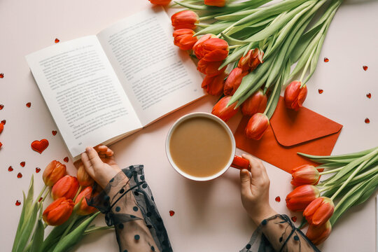 Cup of coffee, open book and bouquet of tulips