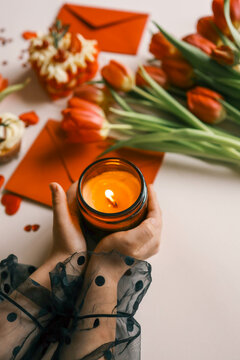 Candle and bouquet of red tulips, spring aesthetics