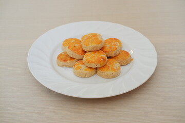 peanut cookies on a white plate on a wooden tablecloth.