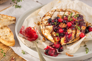 Baked or fried grilled Camembert or brie cheese with berry sauce or jam. Gourmet traditional Breakfast close up.