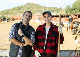 Portrait of a married couple owners of stable against the backdrop of a corral for walking horses