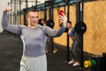 Fototapeta na wymiar Male athlete taking selfie during training in fitness center