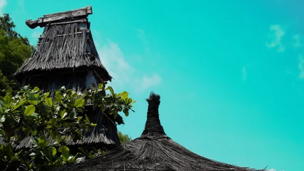 Poster Cultural Timorese house with thatched roof against bright, vibrant aqua sky on tropical island of Timor-Leste, Southeast Asia © Adam Constanza