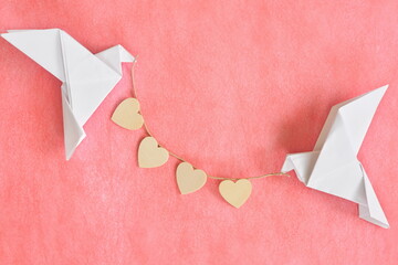 Message of pure love concept. Two white dove origami carrying heart shape on red background.