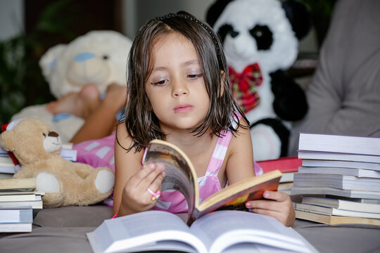 Pausa para Imaginar Crian&ccedil;a deitada Entre Contos e F&aacute;bulas lendo livros no sof&aacute;.