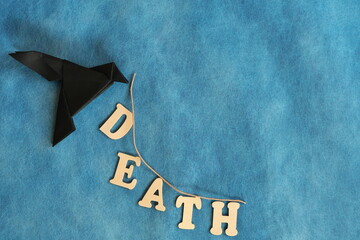 Message of death concept. Black raven or crow paper origami carrying death word.