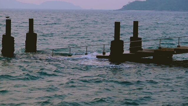 February 1, 2024 - Rawai, Phuket Thailand. Slow motion of small waves gently crashing into the landing pier steps in early morning.