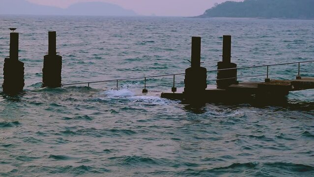 February 1, 2024 - Rawai, Phuket Thailand. Slow motion of small waves gently crashing into the landing pier steps in early morning.