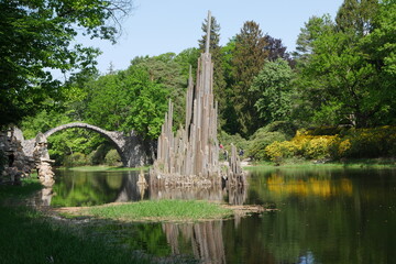Skulptur aus Säulenbasalt und Rakotzbrücke im See im Kromlauer Park