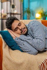 Tired Indian young man lying down in bed taking a rest. Carefree peaceful guy napping, falling...
