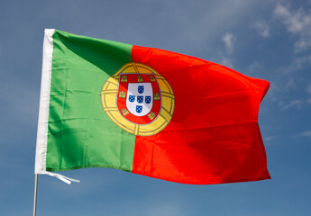 Portuguese nationale green-red flag waved on blue sky background.