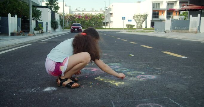 Top view cute sad little girl draw a peace on the asphalt with chalk . Top view of sad child writing peace with chalk. Protest against war, Russian invasion of Ukraine. 4K