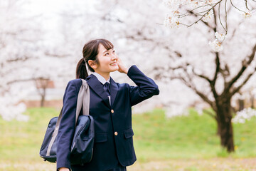 桜の中を歩く中学生・高校生・女子高生・女子高校生
