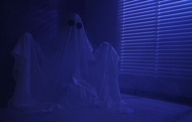 Creepy ghost. Woman covered with sheet near window in blue light, space for text