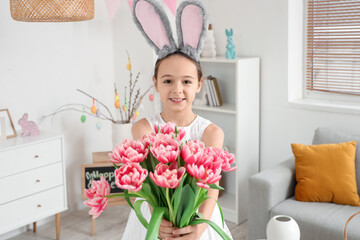 Cute little girl with bunny ears and tulip flowers at home