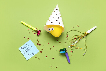 Sticker with text APRIL FOOL'S DAY, balloon and party decor on green background