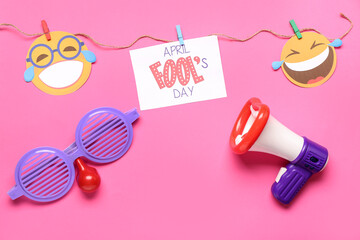 April Fool's Day card with funny glasses, megaphone and decor on pink background
