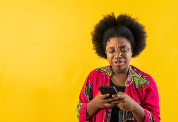 retrato de estudio de joven afroamericana escribiendo por celular mensaje de texto  - obrazy, fototapety, plakaty
