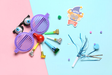 Funny glasses with party whistles and decor on color background. April Fools Day prank