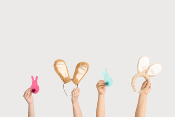 Female hands holding Easter bunny ears headbands and paper rabbits on white background