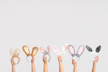 Female hands holding Easter bunny ears headbands on white background