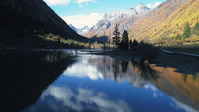 Aerial view of autumn nature landscape of snow mountain range Blue sky, white clouds and snow-capped mountains reflected on the lake water at Siguniang Shan of Sichuan China