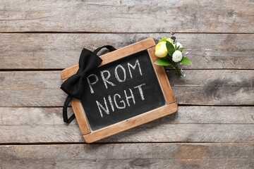 Chalkboard with text PROM NIGHT, bow tie and boutonniere on wooden background - obrazy, fototapety, plakaty