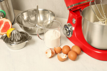 Modern red stand mixer, different products and squeezer on white marble table