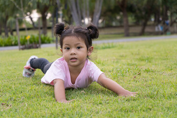 Beautiful baby girl happily plays on the grass.