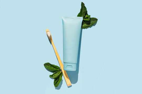 Blue toothpaste tube with fresh mint and toothbrush on blue background