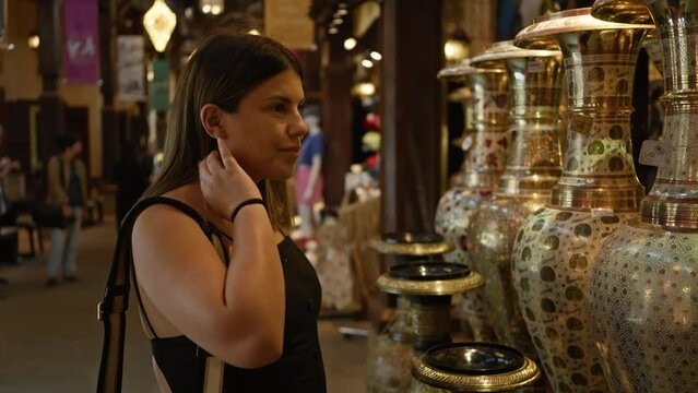 Young woman tourist exploring traditional souk in dubai, admiring arabian crafts.