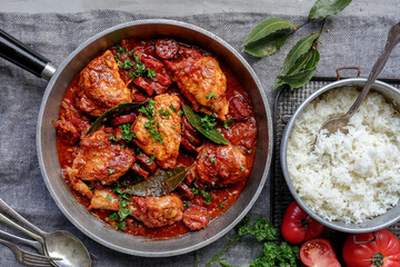 Sauté chicken in a tomato and chorizo sauce in a skillet 