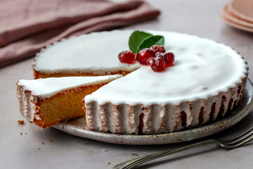 Traditional French almond tart sliced with white icing topped with confit cherries