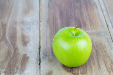 Close up of a green apple on a wooden table.