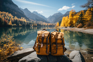 Two yellow backpacks standing near lake during hiking in mountain - obrazy, fototapety, plakaty