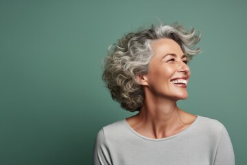 Portrait of smiling middle aged woman with grey hair on green background