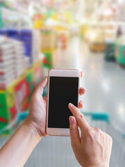 Closeup female hand hold smartphone at supermarket
