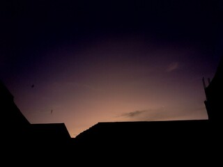 housing silhouette at sunrise with dazzling light colors, wide shot from a lower angle, beautiful Indonesian sunrise