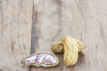 Roasted or row peanuts scattered on rustic, dark wood table background.