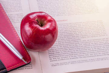 Composition of books, stationery and an red apple on the teacher