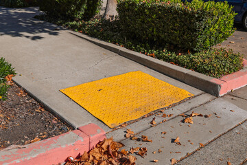 Close-up of disabled sidewalk entry, yellow tactile with a disabled sign to support wheelchair...